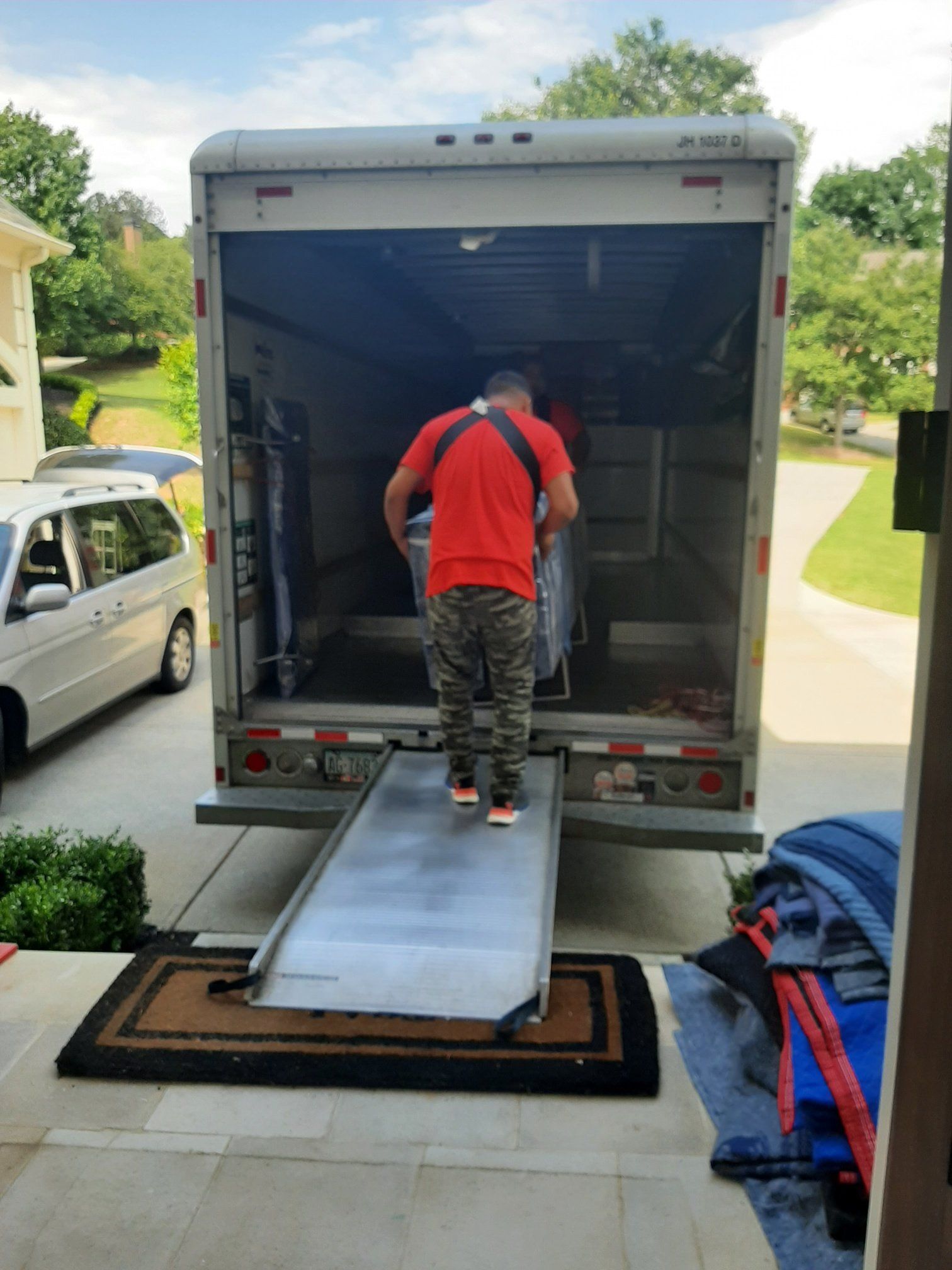 A man in a red shirt is standing in front of a moving truck.