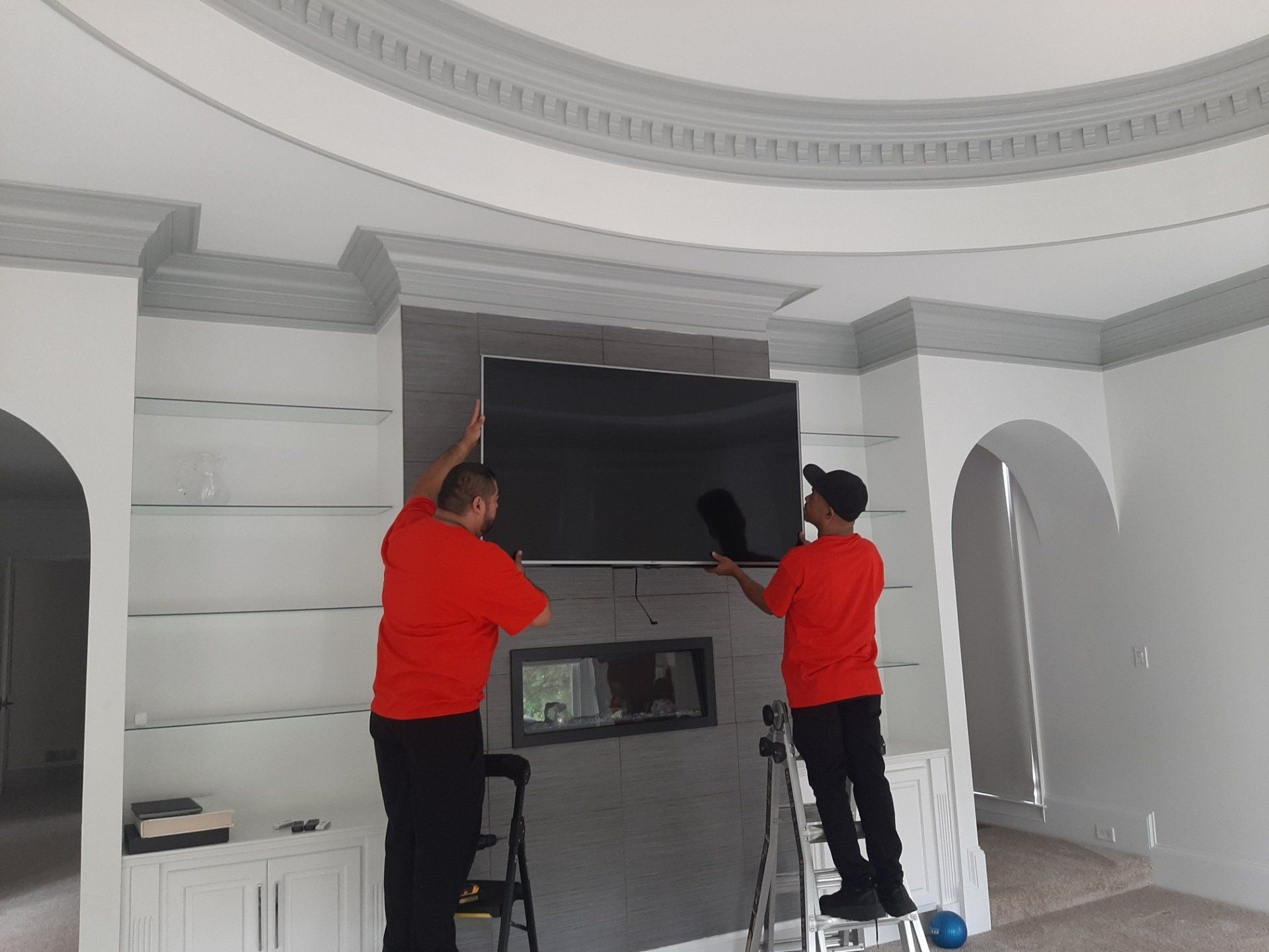 Two men are installing a flat screen tv on a wall.