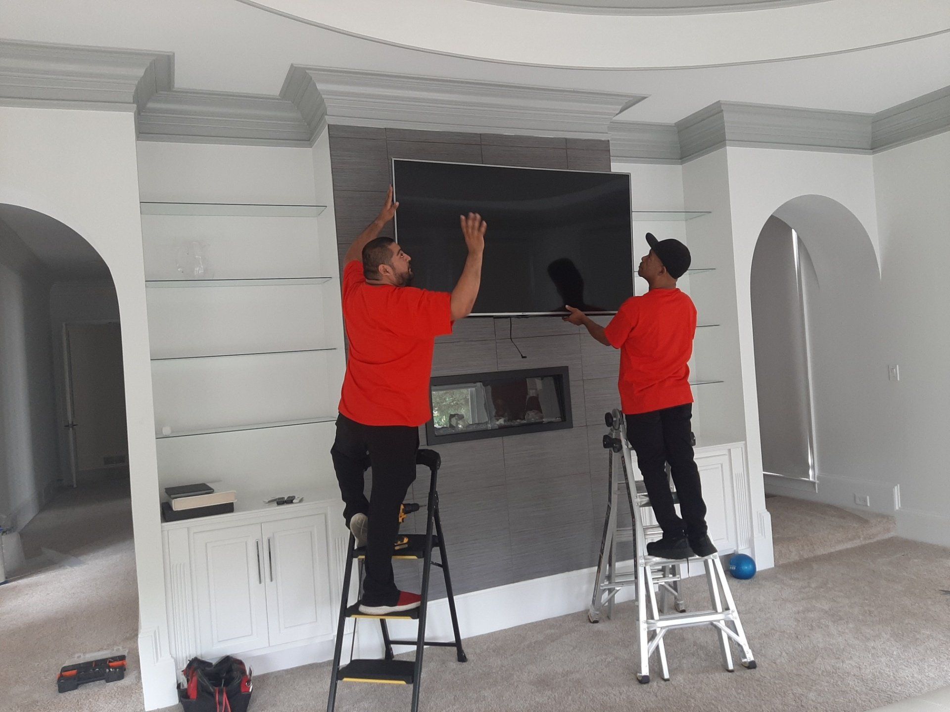Two men are installing a flat screen tv in a living room.