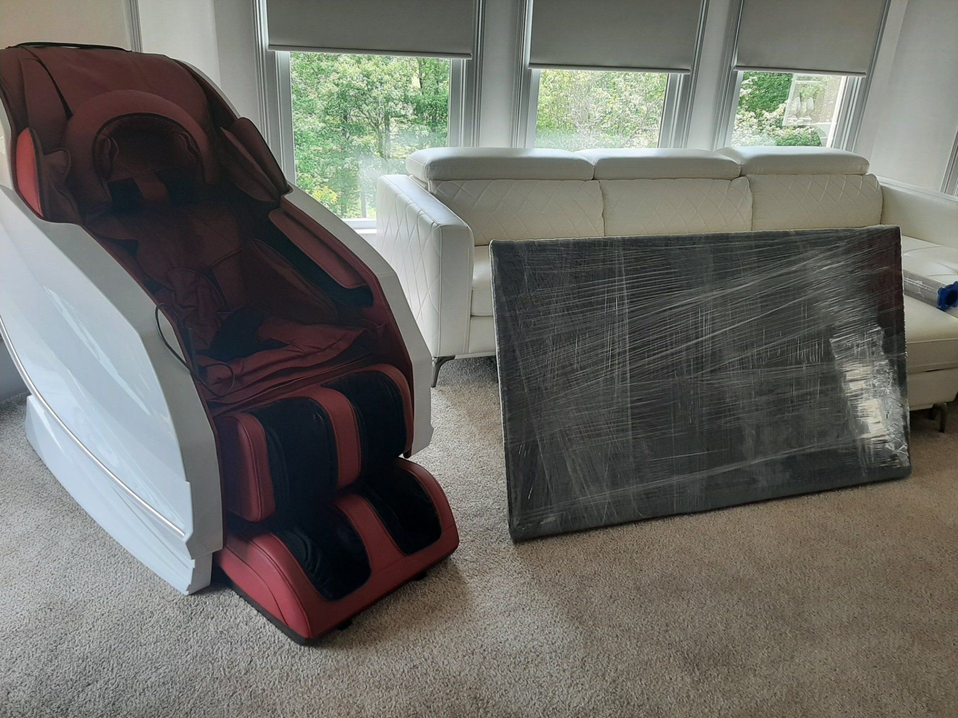 A red massage chair is sitting in a living room next to a couch.