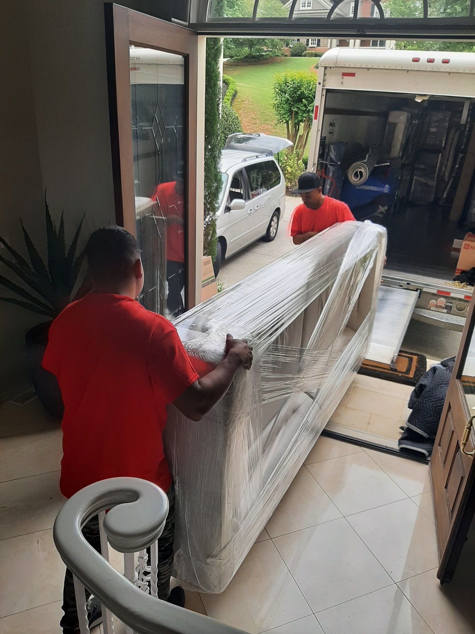 Two men are carrying a large piece of furniture into a house.