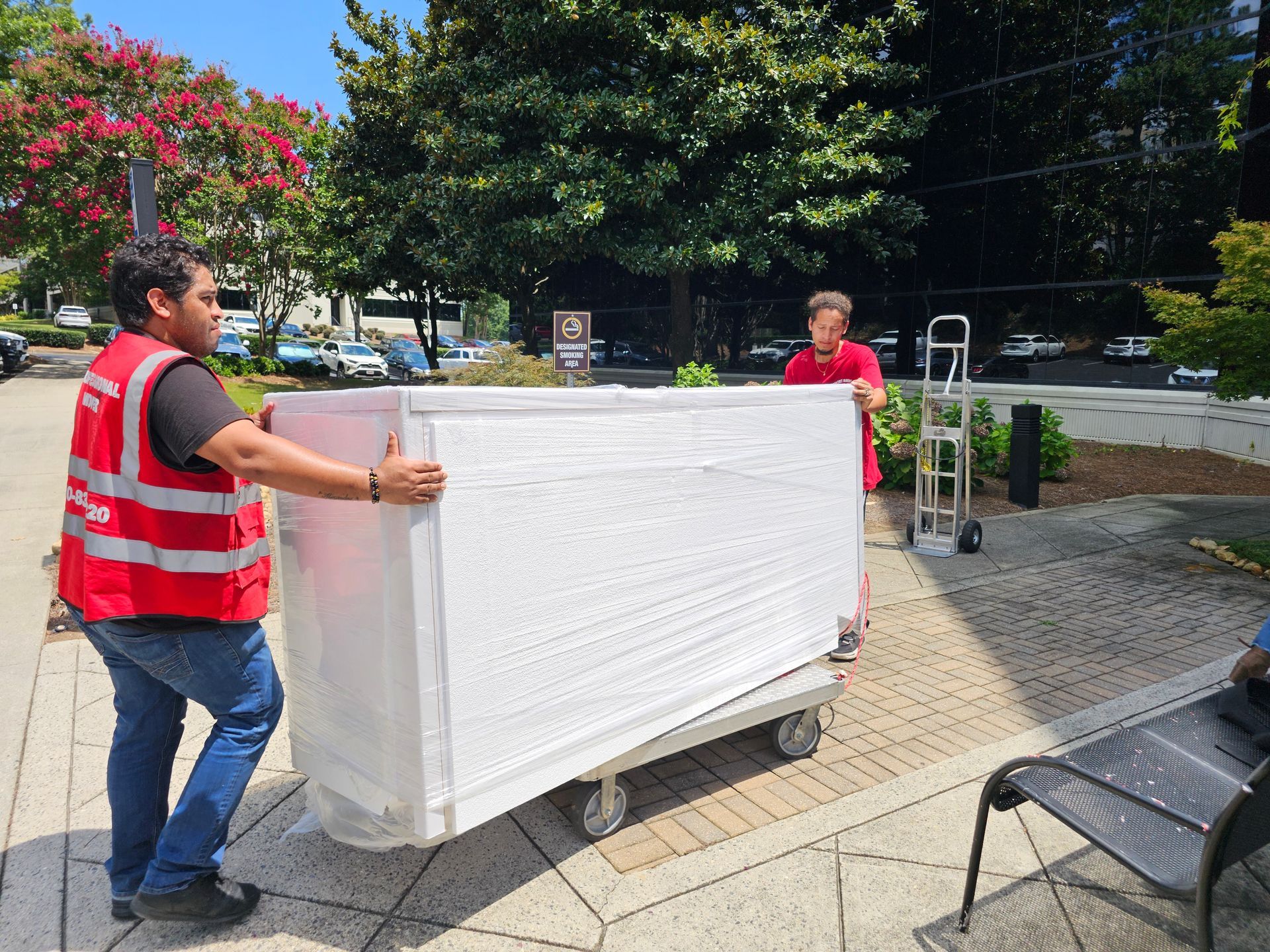 Two men are carrying a refrigerator up a set of stairs.