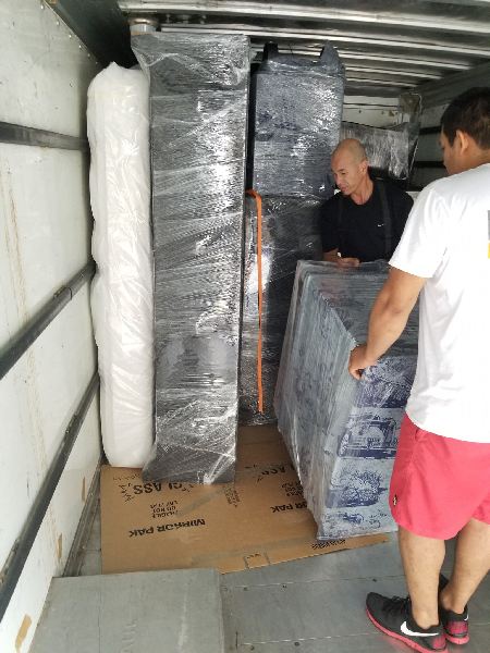 Two men are moving a mattress in a truck.