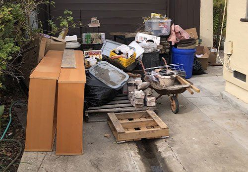 A pile of trash is sitting on the sidewalk in front of a garage.