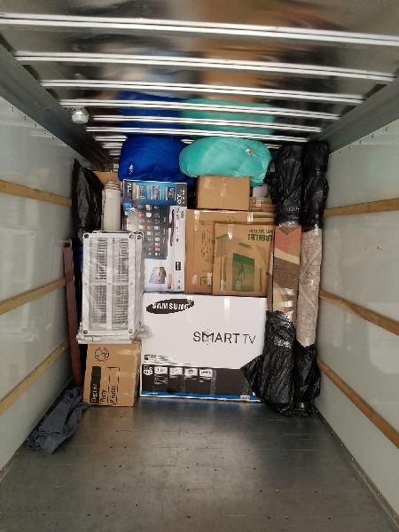 The inside of a moving truck filled with boxes and a smart tv.