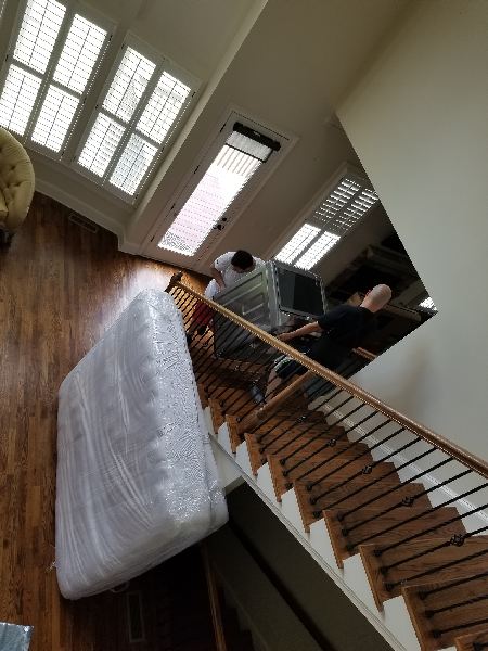 A man is carrying a mattress up a set of stairs.