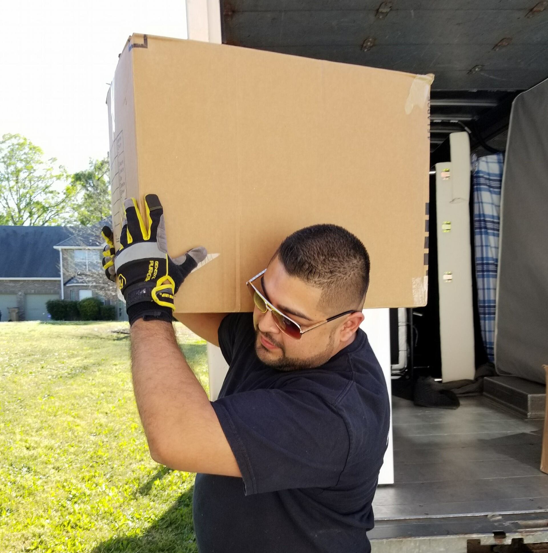 A man is carrying a large cardboard box on his head