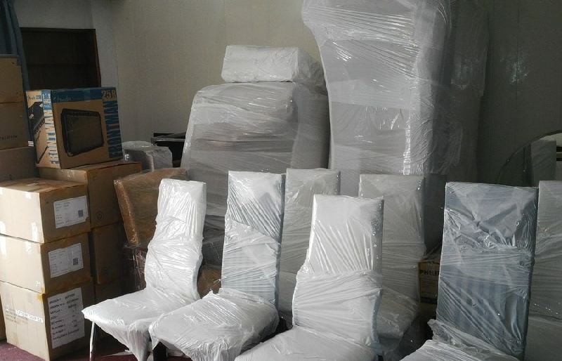A room filled with boxes and chairs wrapped in plastic.