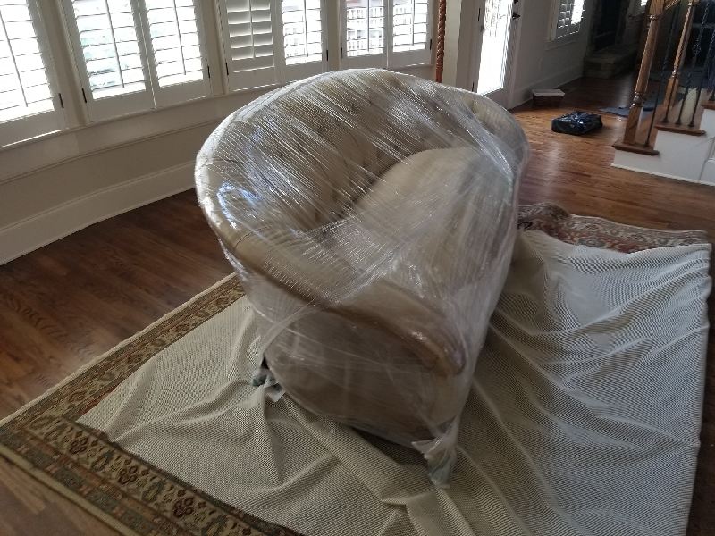A chair wrapped in plastic is sitting on a rug in a living room