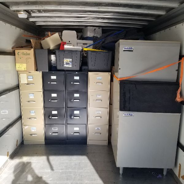 The inside of a truck filled with filing cabinets and safes