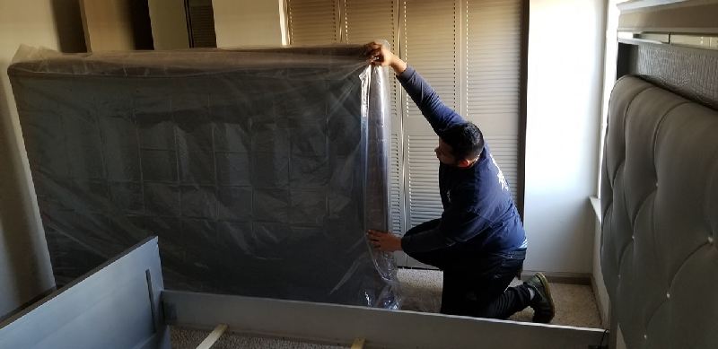 A man is kneeling down in a room holding a piece of plastic.