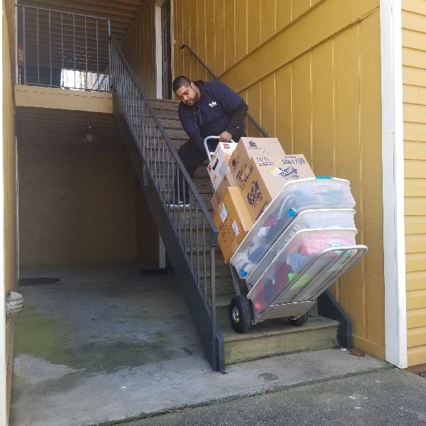 A man is pushing a cart full of boxes up a set of stairs