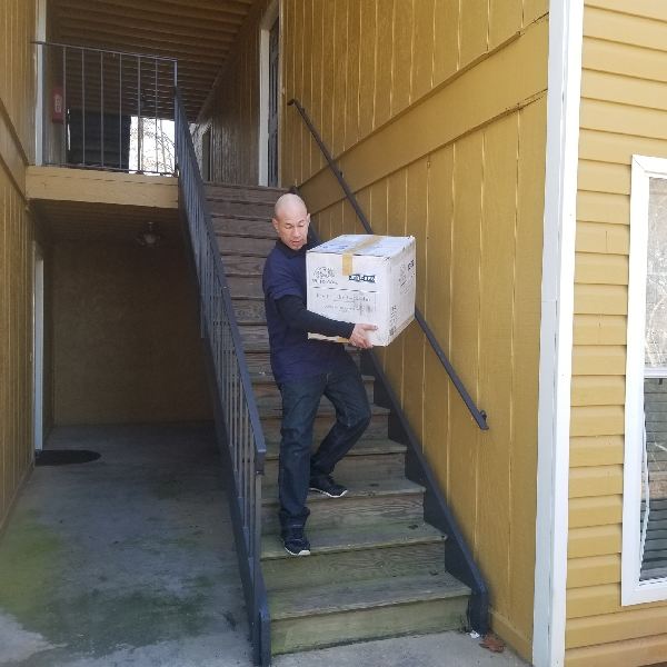 A man is carrying a cardboard box up a set of stairs