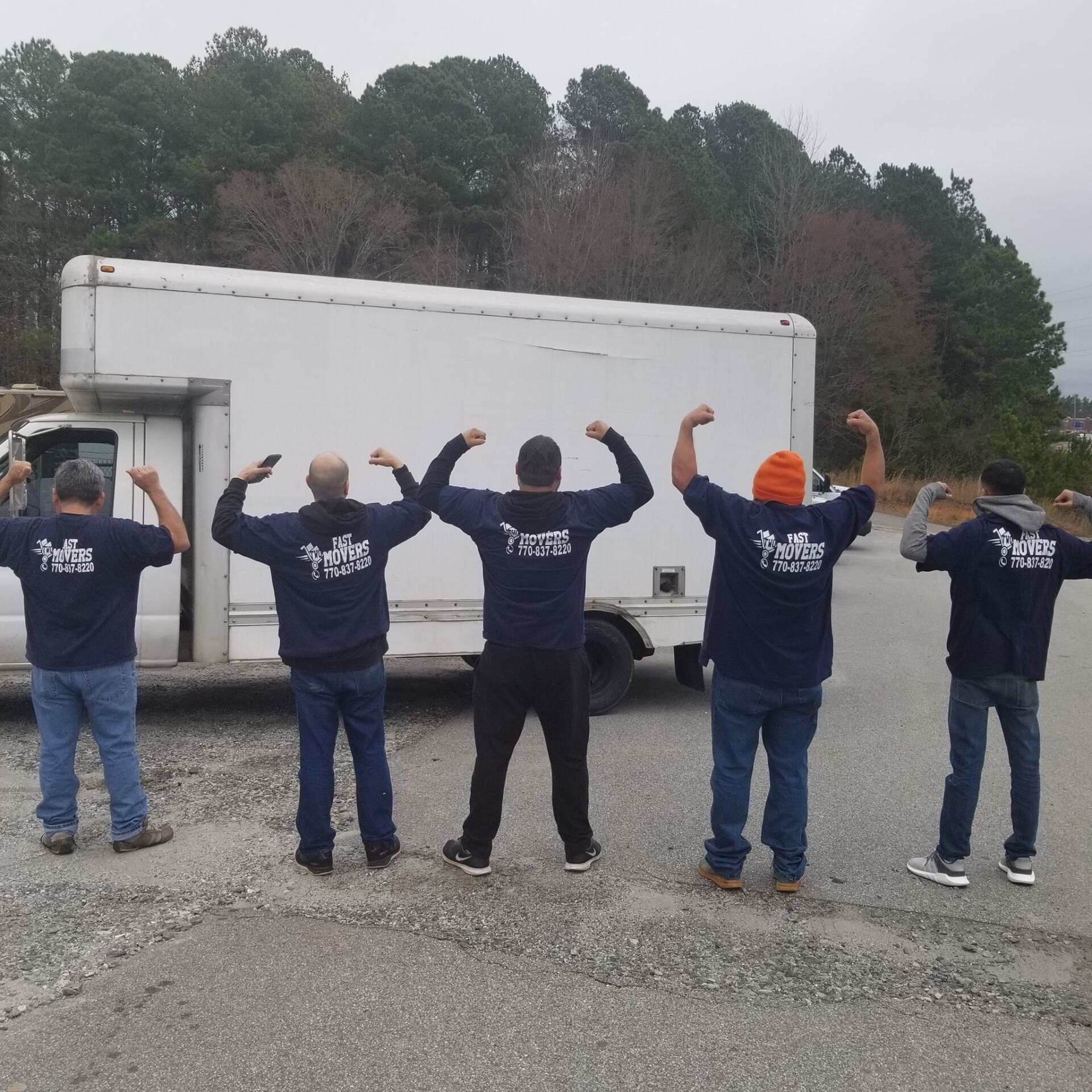 A group of men are flexing their muscles in front of a white truck