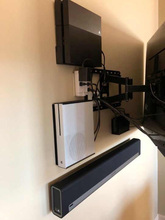 A tv mounted to a wall with a xbox and a sound bar