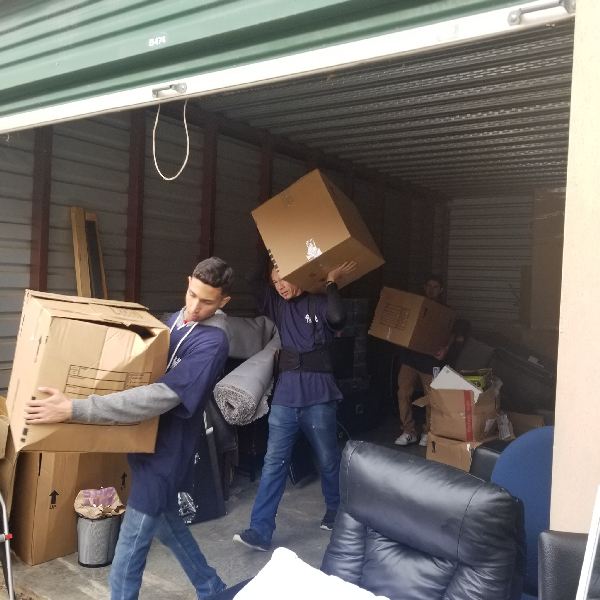 Two men are carrying boxes in a storage unit