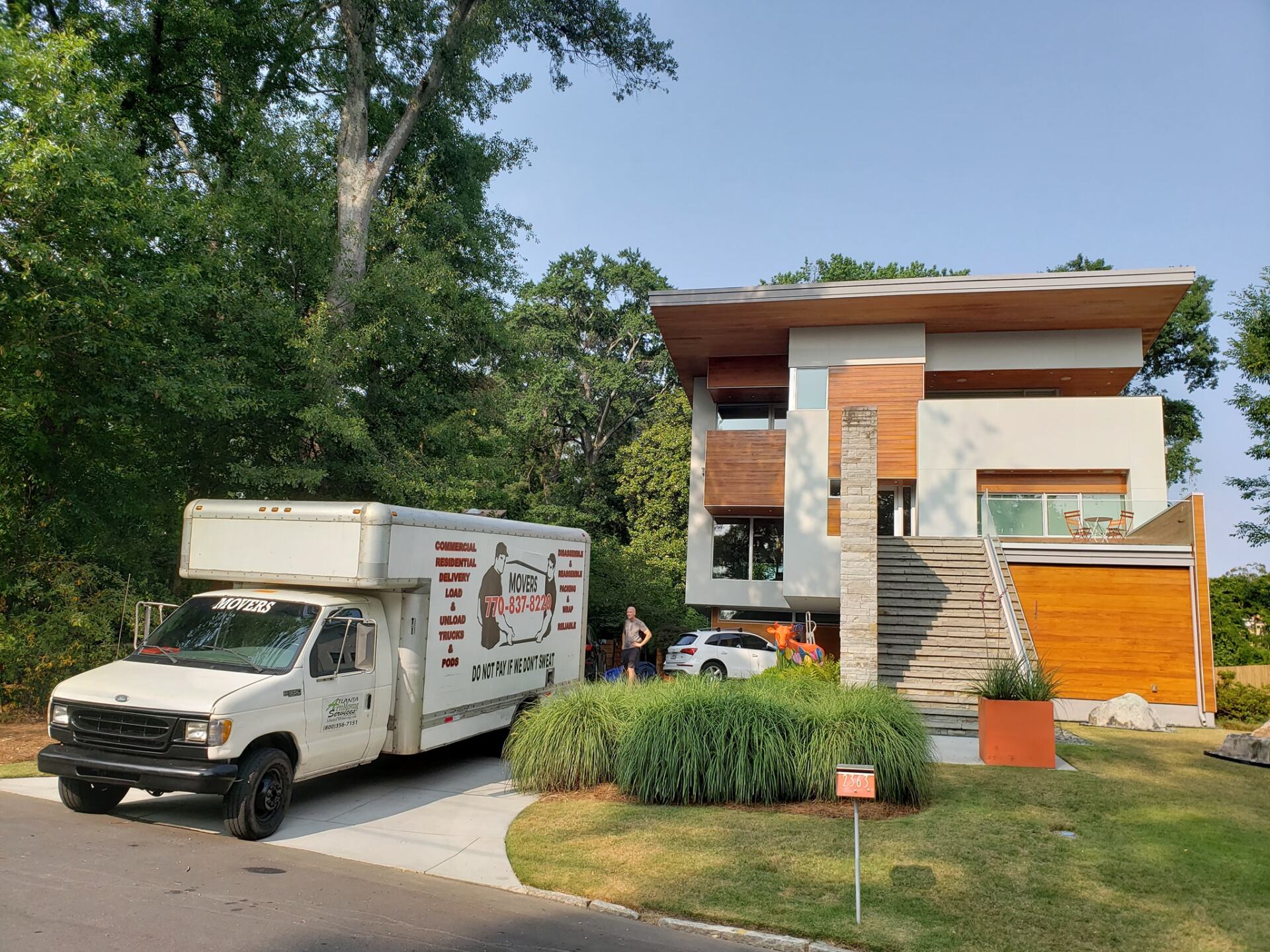A moving truck is parked in front of a modern house.