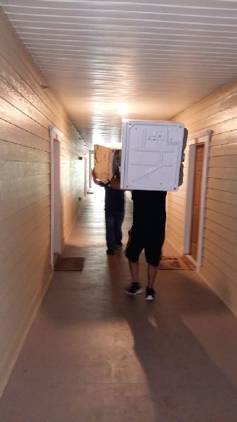 Two men are carrying boxes down a hallway.