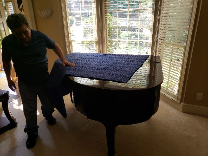 A man is moving a piano in a living room.