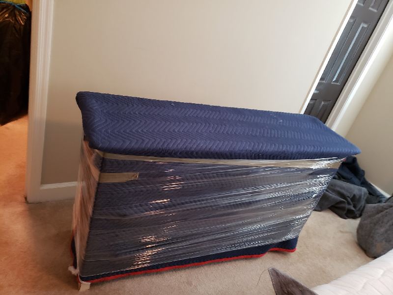 A blue box wrapped in plastic is sitting on the floor in a room.