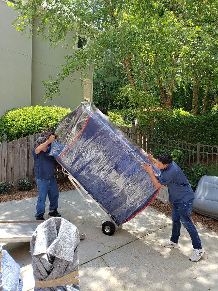 Two men are moving a couch on a dolly.