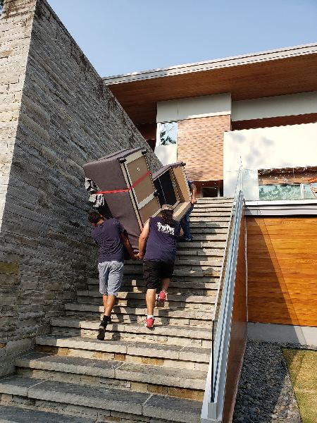 Two men are carrying a refrigerator up a set of stairs.