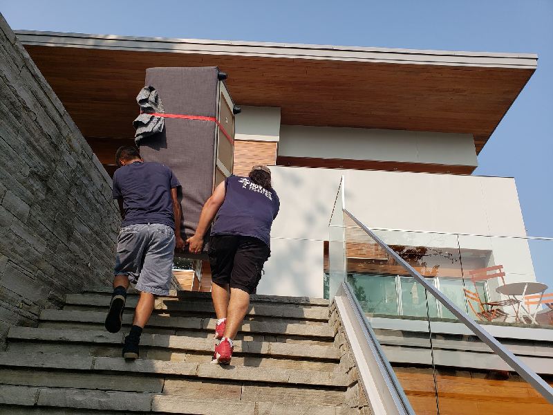 Two men are carrying a large piece of furniture up a set of stairs.