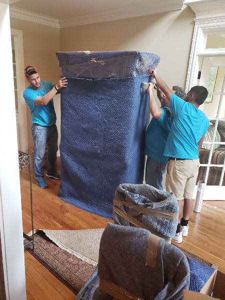 A group of men are moving a large item in a living room.