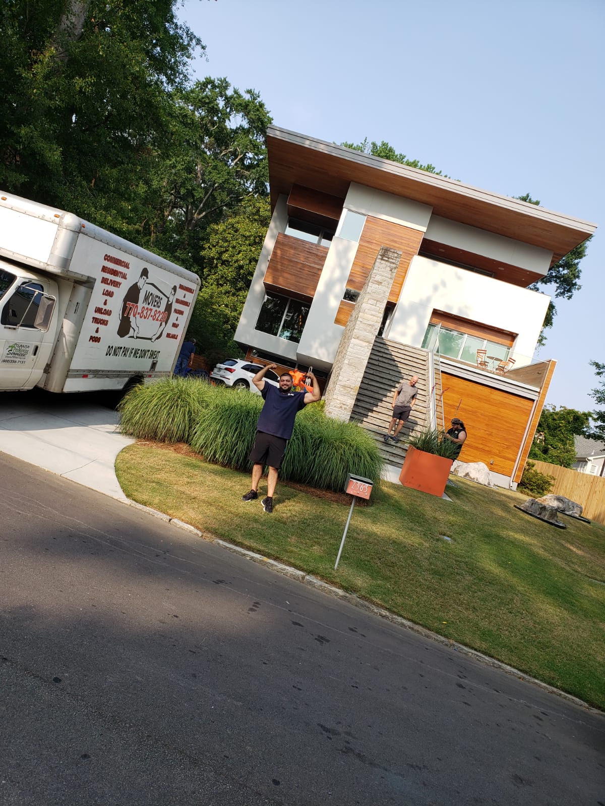 A man is standing in front of a house next to a moving truck.