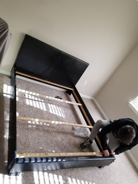 A man is working on a bed frame in a bedroom