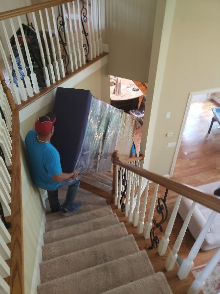 A man is carrying a couch up a set of stairs