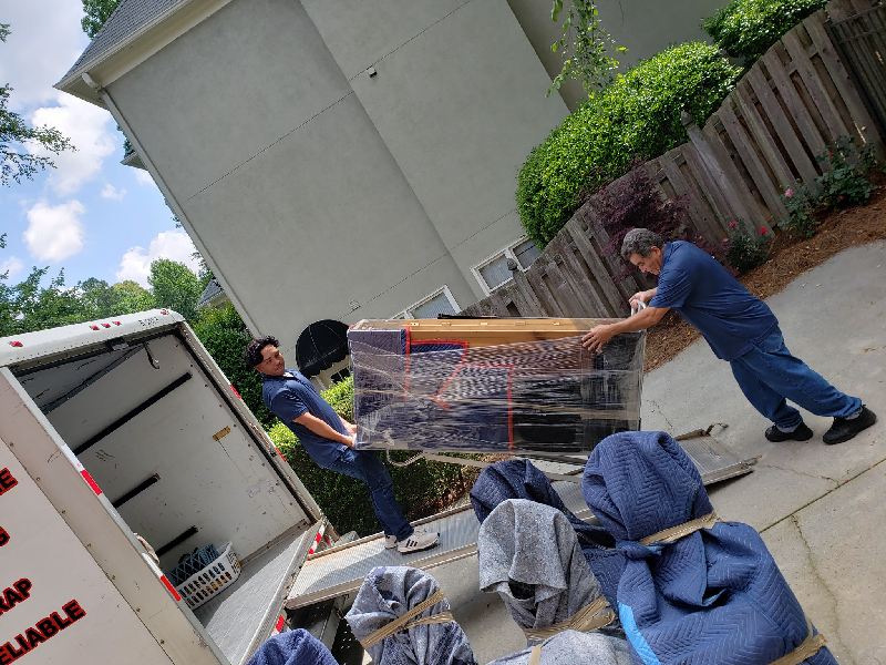 Two men are carrying a large piece of furniture out of a moving truck.