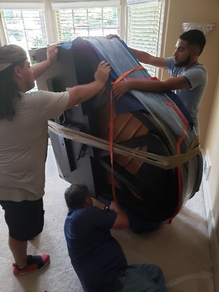 Two men are carrying a large piano in a room.