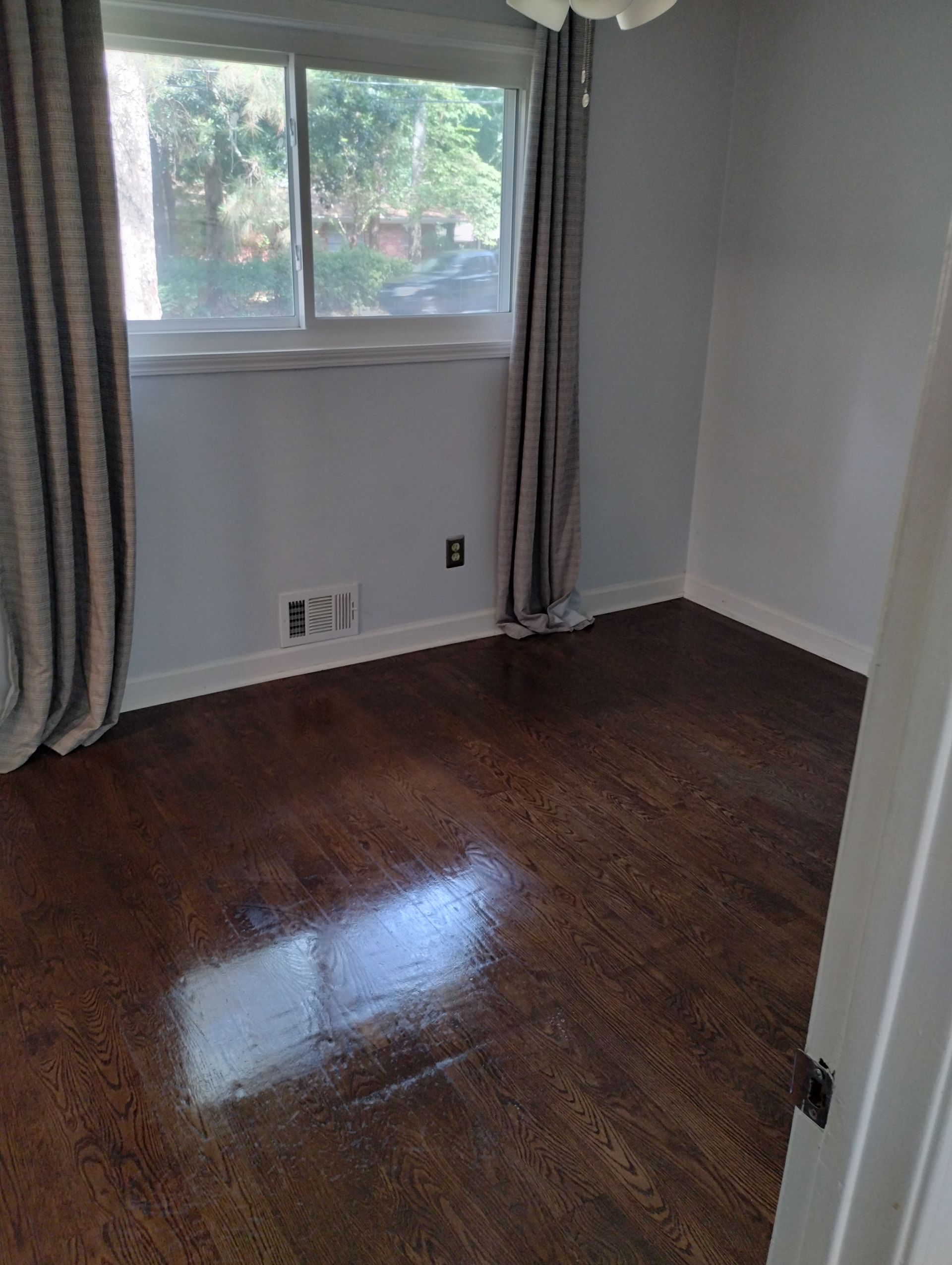 An empty room with hardwood floors and a window.