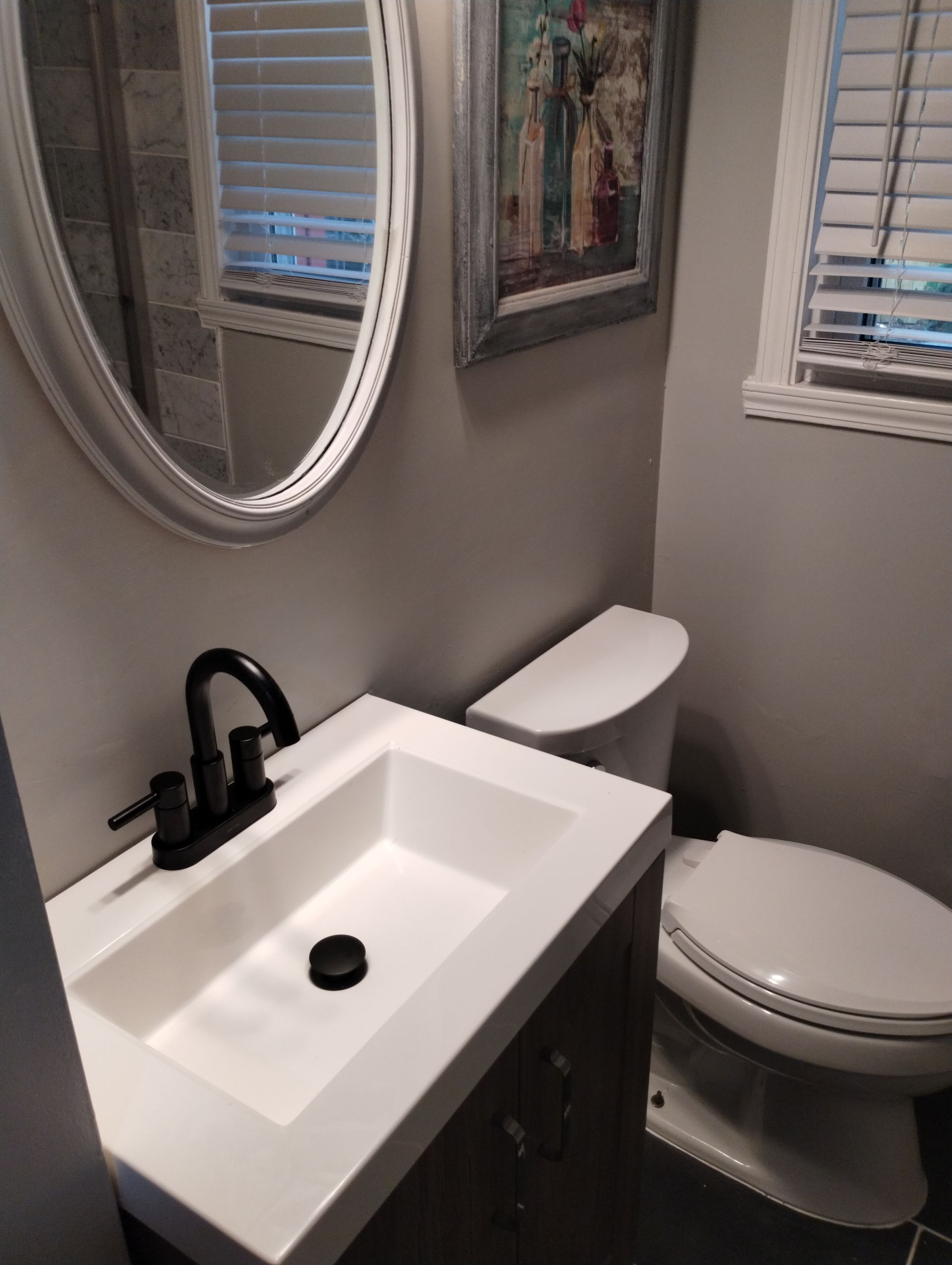 A bathroom with a sink , toilet and mirror.