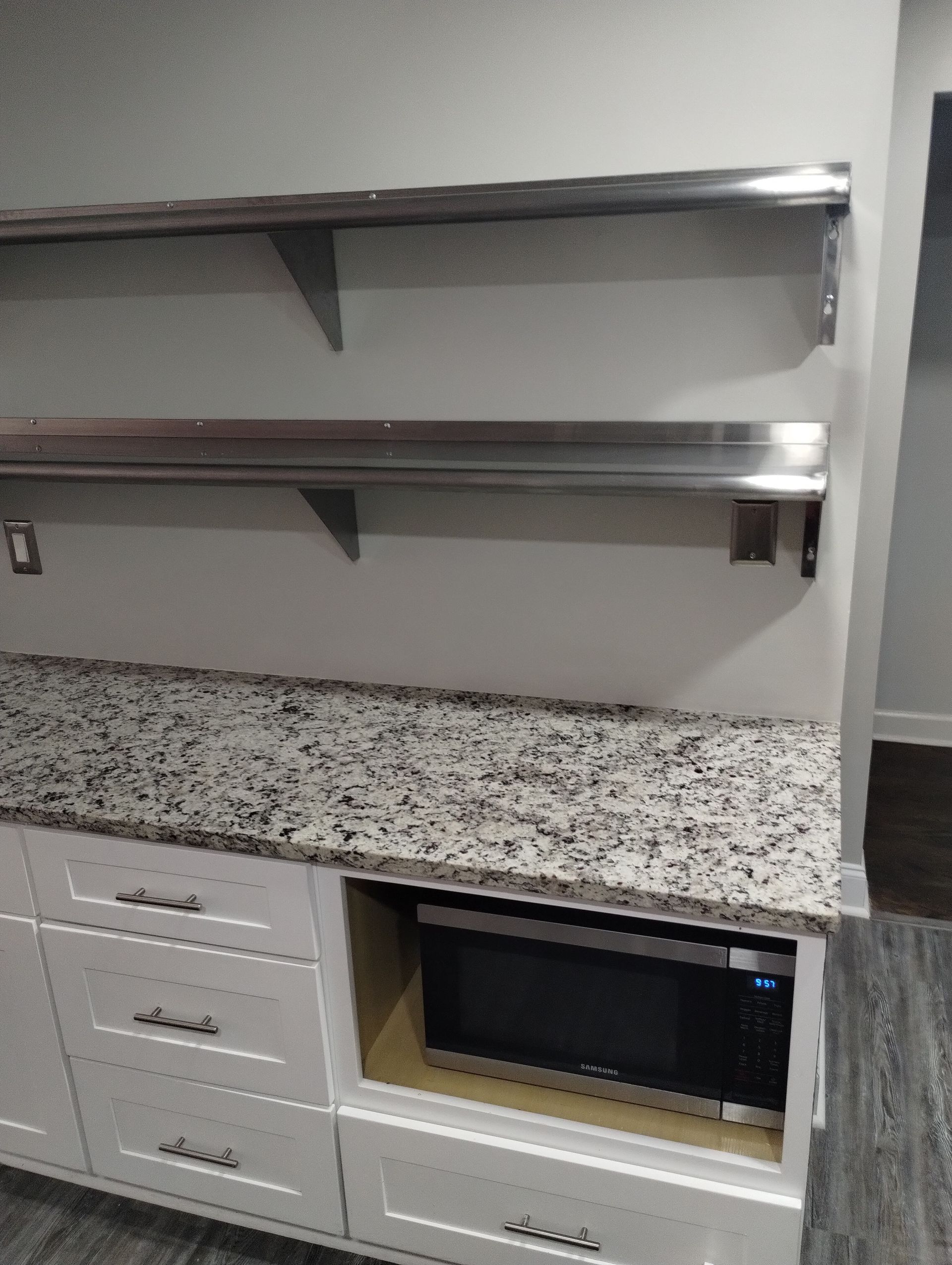 A kitchen with granite counter tops and stainless steel shelves.