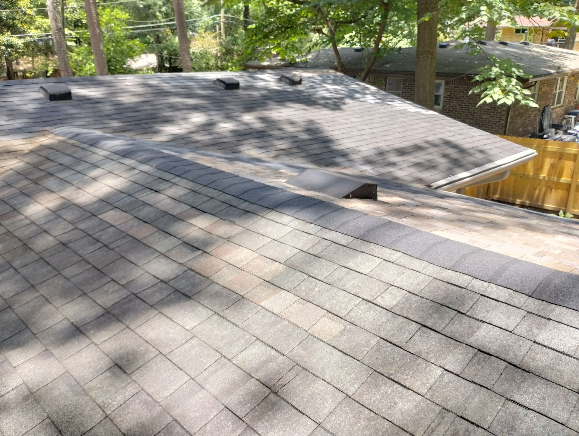 A roof with a lot of shingles on it and trees in the background.
