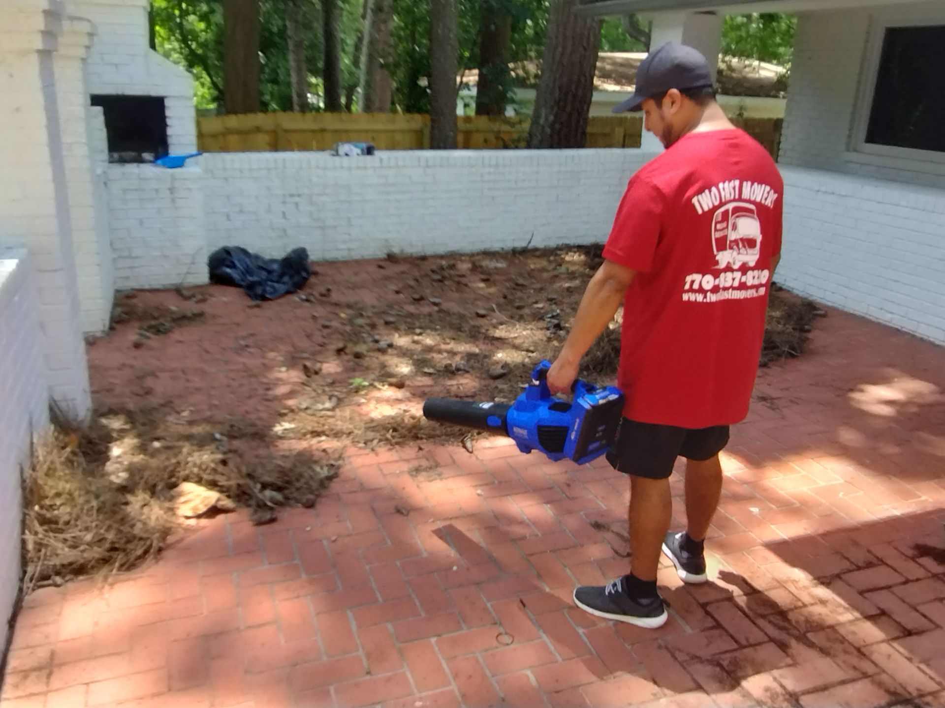A man in a red shirt is holding a blue blower.