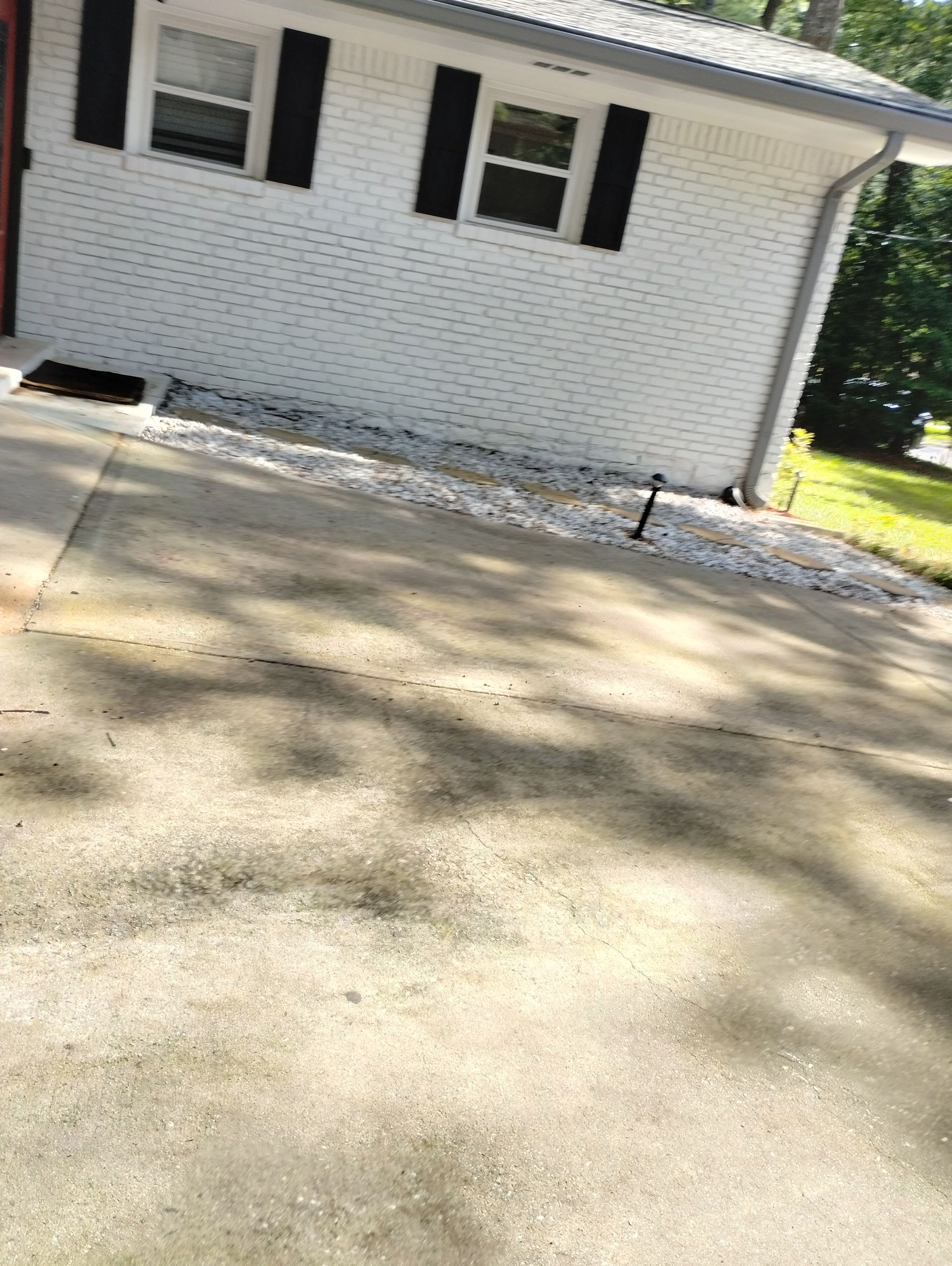 A white house with black shutters and a driveway in front of it.