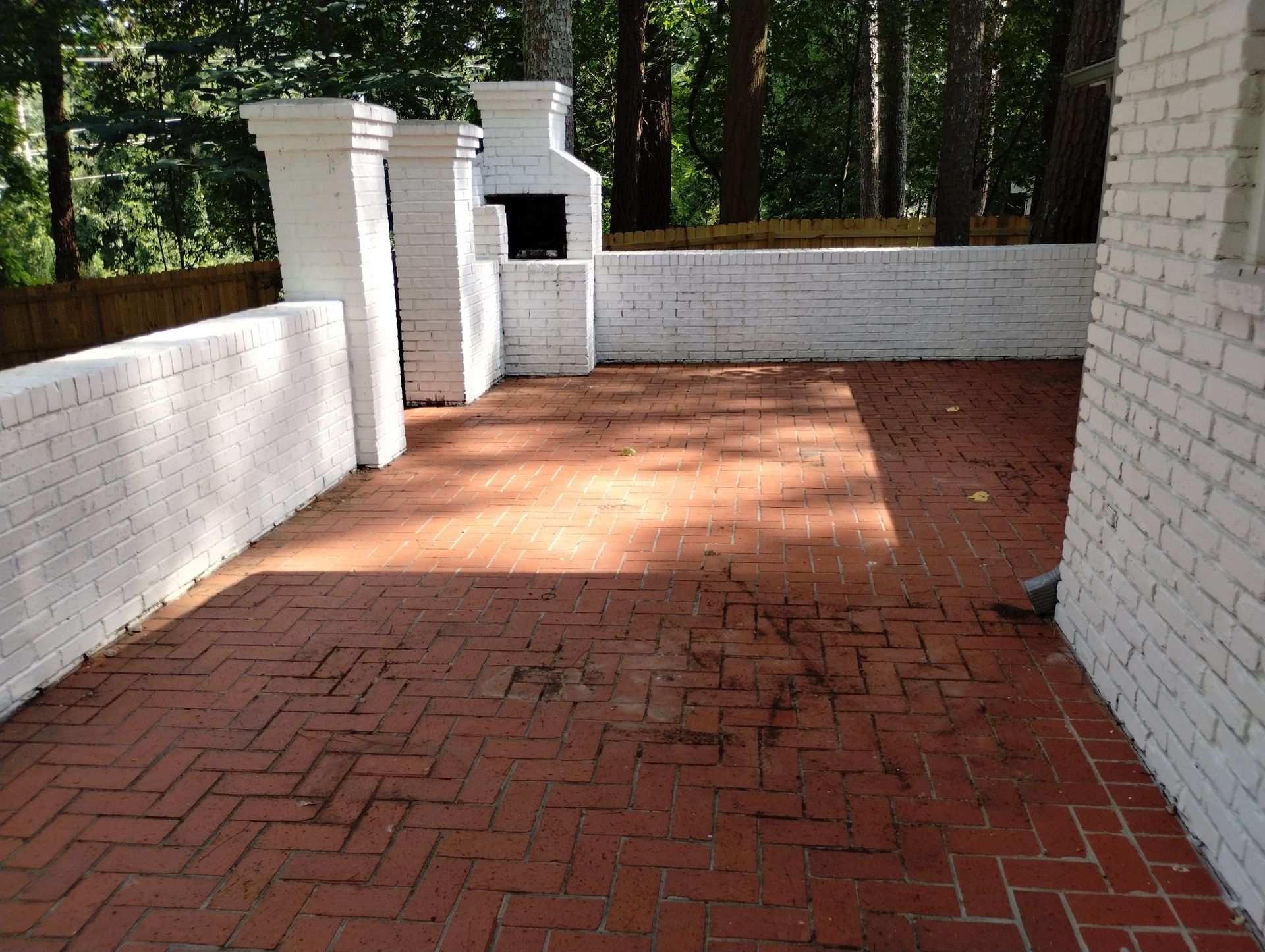 A brick patio with a white brick wall behind it