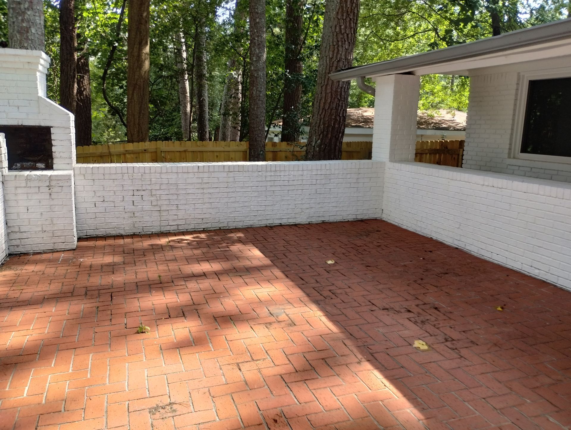 A brick patio with a white brick wall and a fireplace.