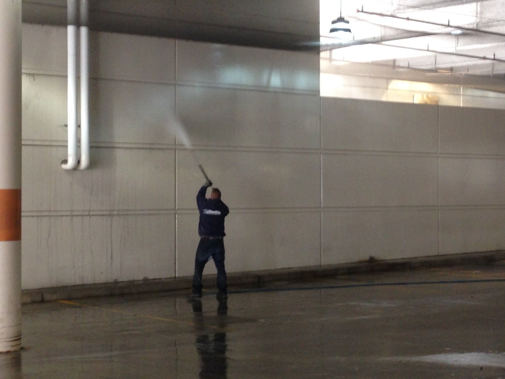 A man is using a high pressure washer to clean a wall