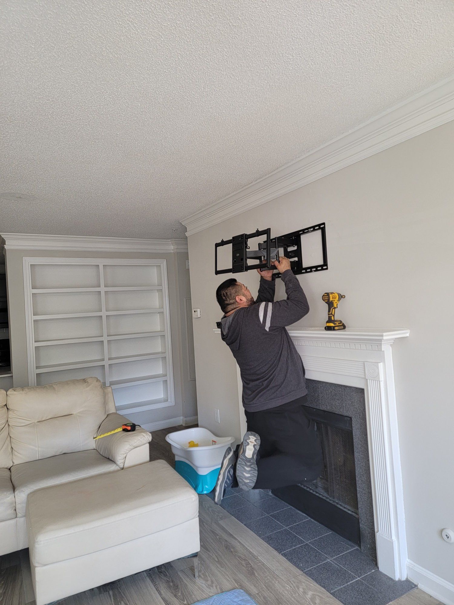 A man is installing a tv mount on a wall in a living room.