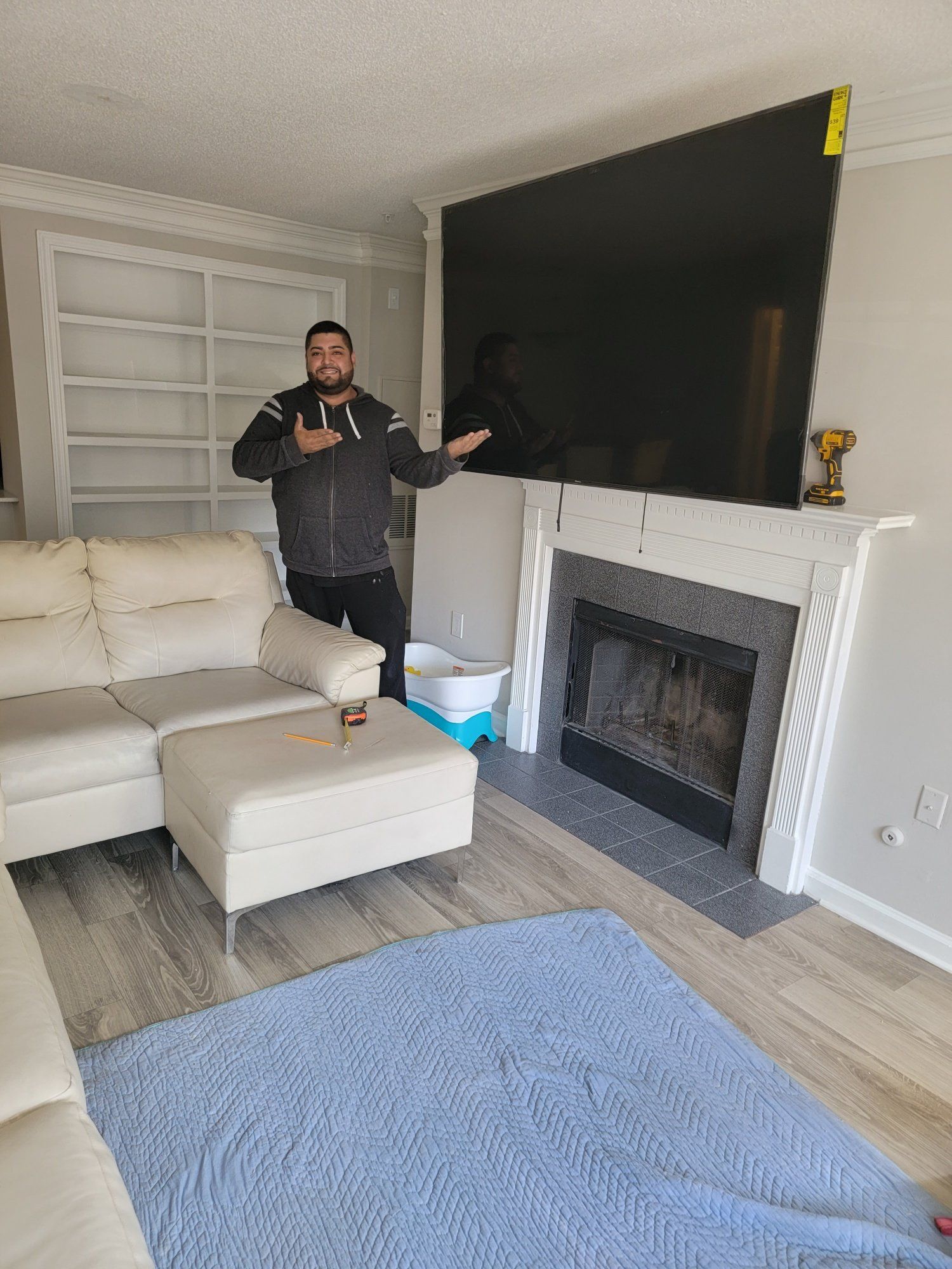 A man is standing in a living room next to a couch and fireplace.