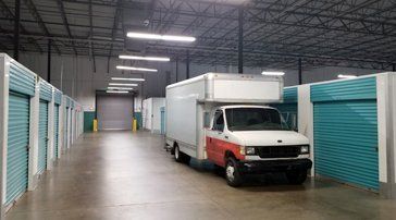 A white and red moving truck is parked in a warehouse.