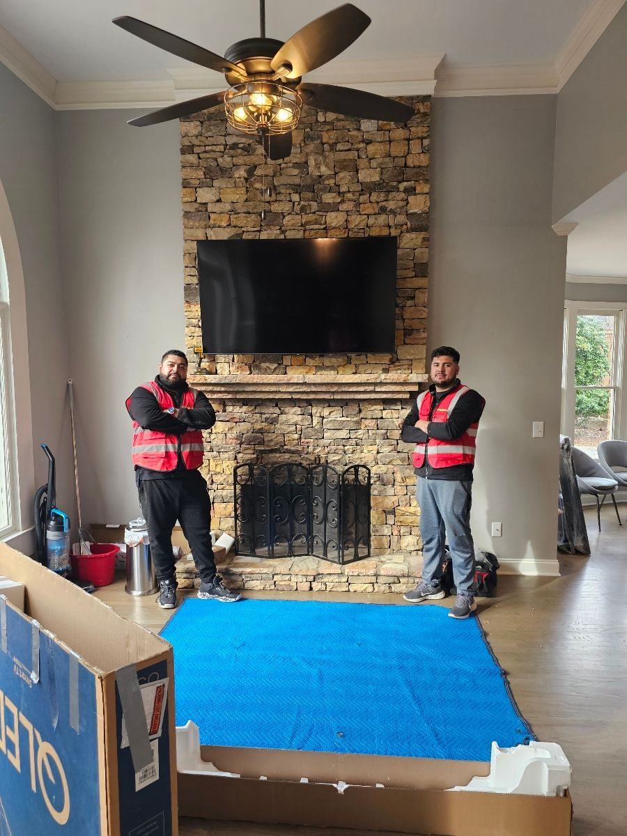 A man is wrapping a chair in plastic wrap in a living room.