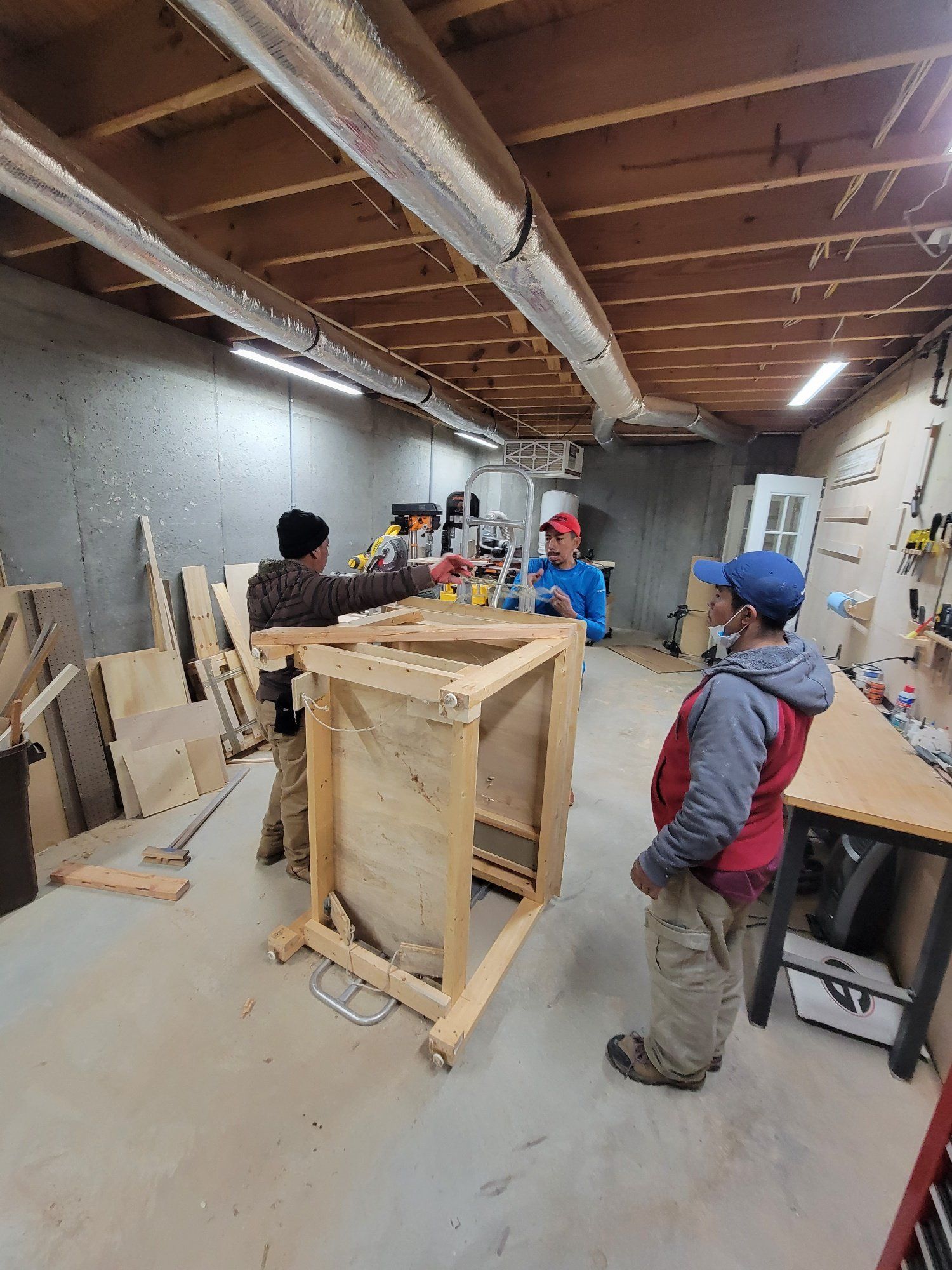 A group of people are working on a wooden box in a garage.