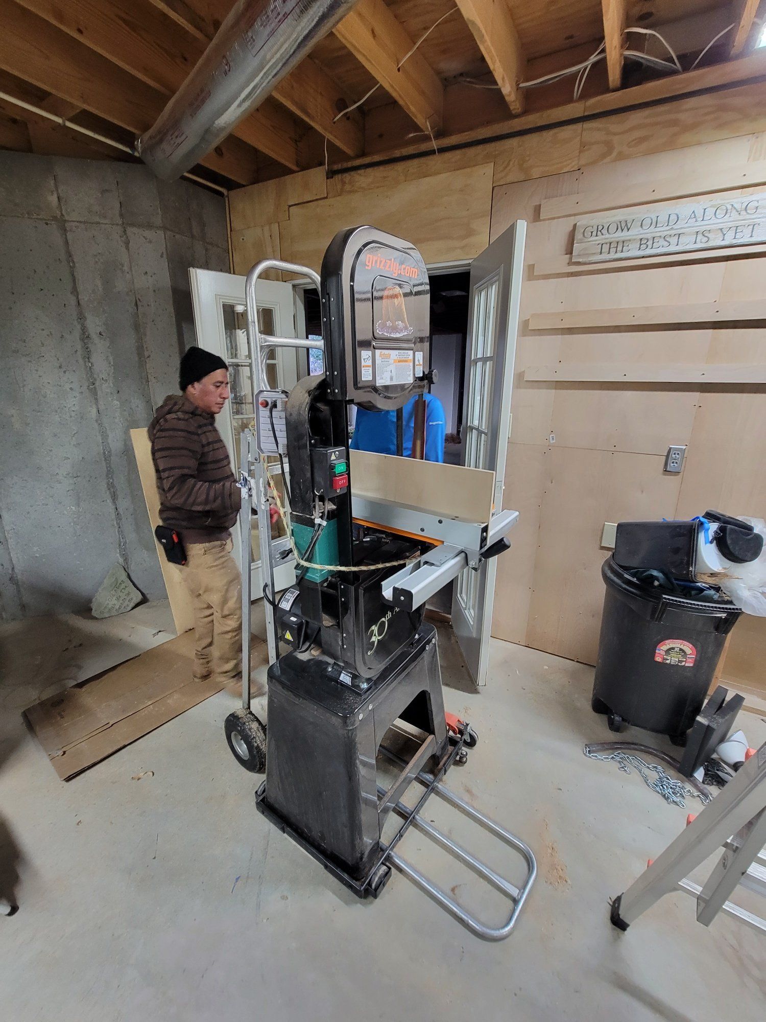 A man is standing next to a band saw in a garage.