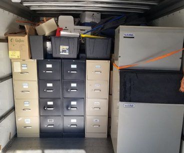 A truck is filled with filing cabinets and safes