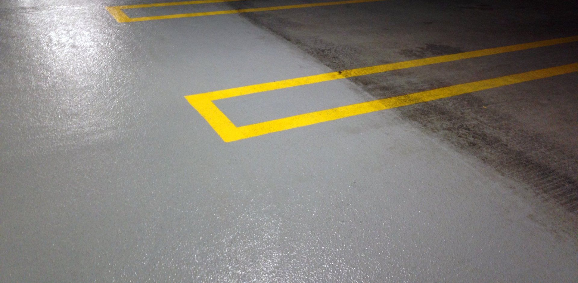 A close up of a parking lot with yellow lines on the floor.